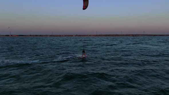 Kite Surfer Is Gliding on Water on High Speed in the Evening Colorful Sky