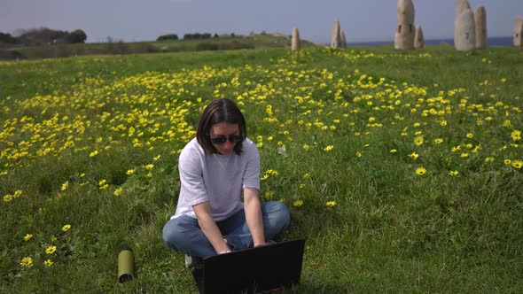 The Girl Works at the Computer Sitting on the Green Grass