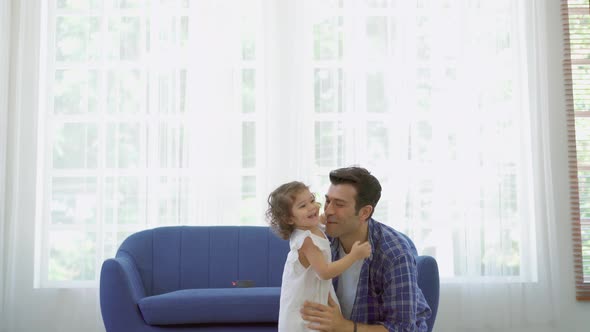 Happy affectionate family. Caucasian man father playing and carrying little daughter at sofa. 