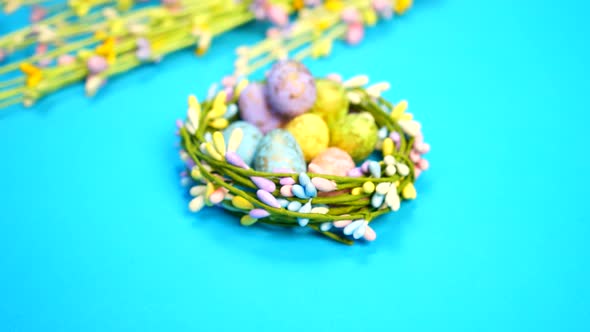 Forwardement shot of Easter eggs in the nest on blue background. Greetings and presents for Easter D