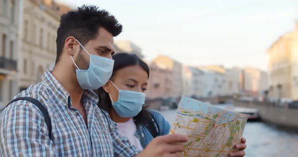 Couple with Face Mask Looking at Map Exploring Foreign City and Traveling During Pandemic