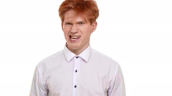 Mad Disheveled Caucasian Ginger Young Man Expressively Standing on White Background and Pointing His