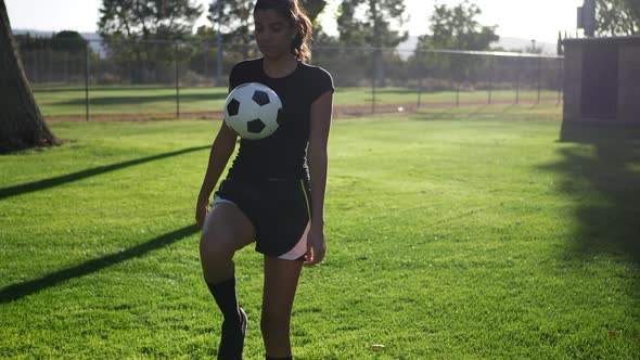 A young woman soccer player juggling and kicking a football during a team women sport practice.