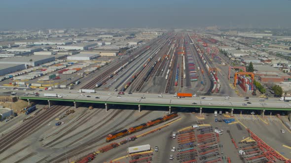 Aerial of vehicle driving on highway and shipping yard on either sides