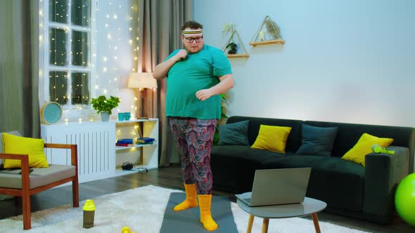 An Obese Man is on a Blue Workout Mat in a Living