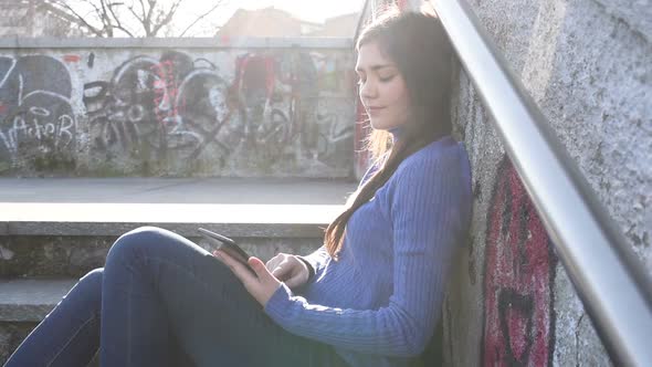 Young woman outdoor backlight using tablet