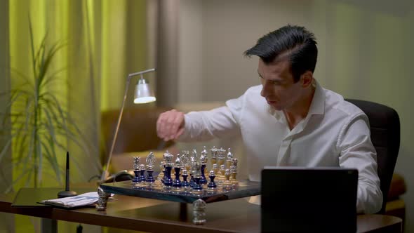 Thoughtful Young Middle Eastern Man Playing Chess at Home Checking Online Video