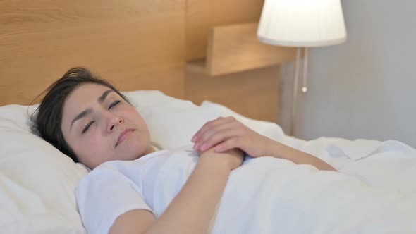 Young Indian Woman Waking up from Sleep in Bed