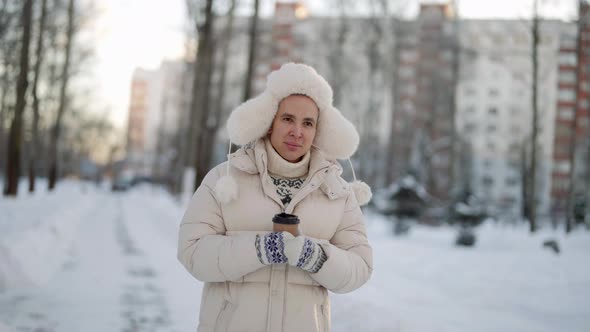 Young Man is Walking in City in Winter Drinking Hot Tea or Coffee From Paper Cup