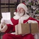 Cheerful Kind Grandfather in Santa Carnival Costume Reads a Child's Letter with Desired Gifts While - VideoHive Item for Sale