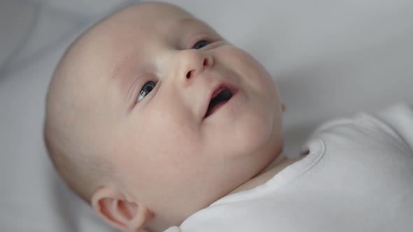 Newborn Baby Smiling and Gesturing in Bed