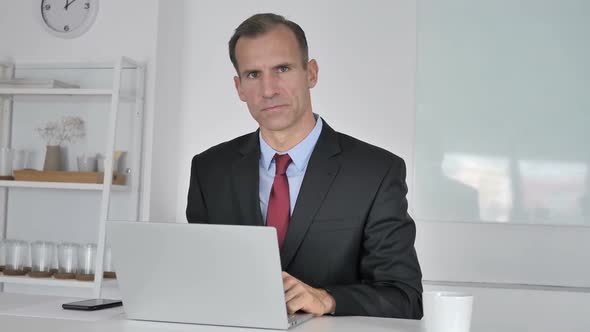 Thumbs Down By Middle Aged Businessman Looking at Camera