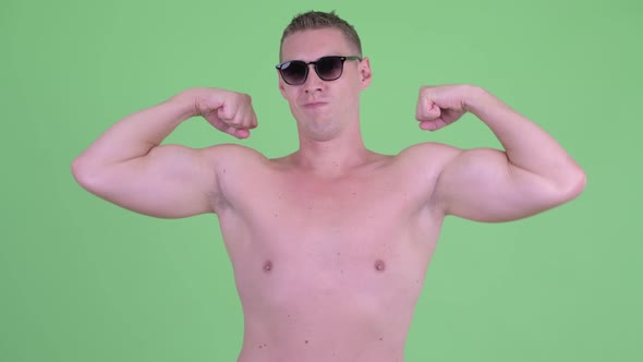 Happy Shirtless Young Man Flexing Both Arms