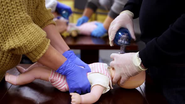 Demonstrating chest compressions on medical infant dummy doll