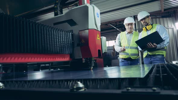 Male Workers Are Inspecting a Laser-cutting Machine