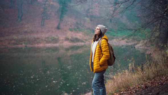 A Young Adult Woman Standing at the Forest Lake and Taking a Deep Breath