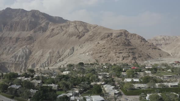 Aerial fly over small kibbutz in Israel desert in front of a rock mountain