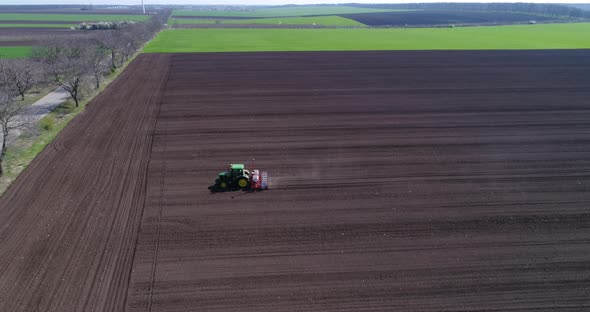 4k aerial view of tractor sowing wheat or sunflower in agriculture area