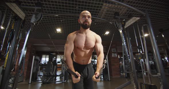Muscular Bodybuilder Doing Cross Training Machine Pumping Big Pectoral Muscles