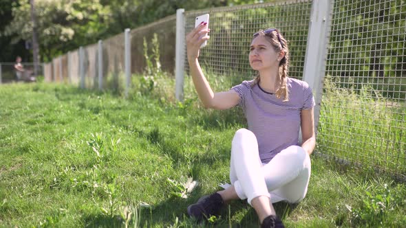 Attractive Young Woman Uses Smatphone in Park at Day