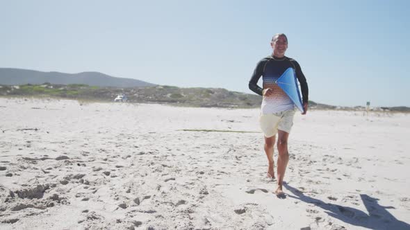 Senior Caucasian man holding a surfboard on the beach