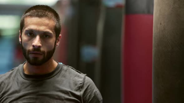 Young Sweaty Boxer Portrait Resting Near Punching Bag in Gymnasium