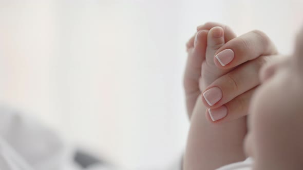 Gentle Female Hand Holding Hand of Newborn Baby