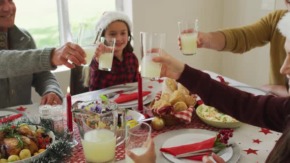 Happy caucasian multi generation family wearing santa hats, having christmas meal