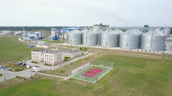 Aerial view of grain elevators surrounded by green fields.