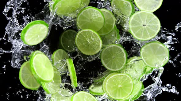 Super Slow Motion Shot of Rotating Exploded Lime Slices with Splashing Water on Black at 1000Fps