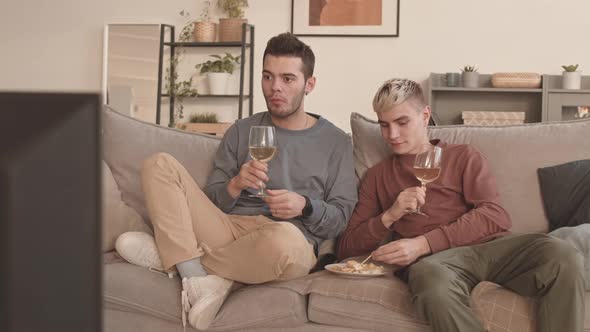 Gay Couple Drinking Wine and Watching Film on TV