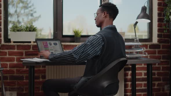 African American Worker Planning Commercial Report on Laptop