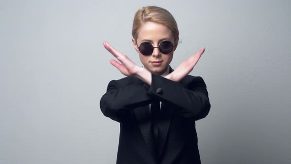 businesswoman in a classic business suit and sunglasses show prohibition symbol