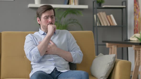 Young Man Coughing While Sitting on Sofa