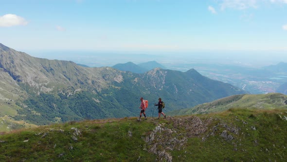 Aerial: couple backpackers hiking on mountain top Summer adventures on the Alps