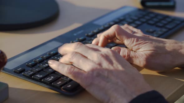 Close shot of the hands of a man typing on a computer keyboard.