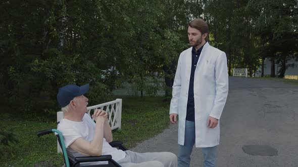 Doctor in White Medical Suit Chat with Handicapped Person