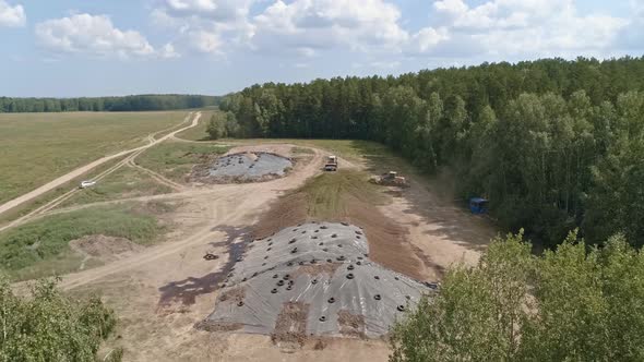 Aerial view of tractors tamp the silage in the Silo Trench next to the forest 03