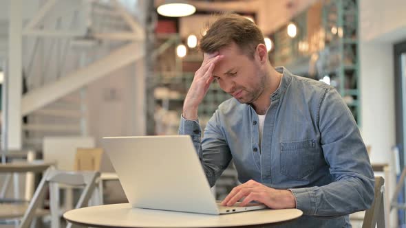 Casual Man with Headache Using Laptop in Cafe