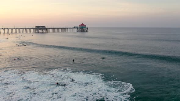 Surfers catch a wave as the sun rises over the pier in Surf City USA Huntington Beach Southern Calif