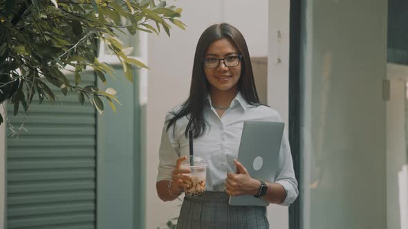 Beautiful Young Woman Walks at Business Downtown in Morning Holding Laptop in Hands