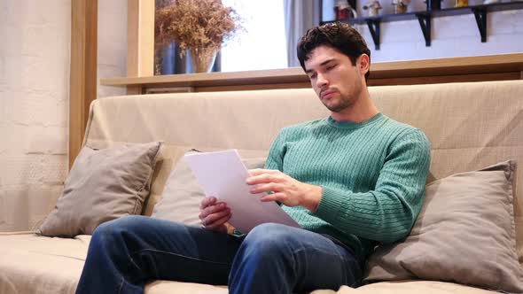 Paperwork Man Reading Documents Sitting on Couch at Home