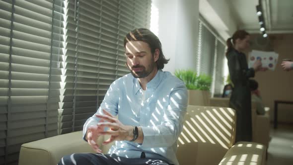 A Young Businessman is Sitting on the Sofa and Talking to His Colleague