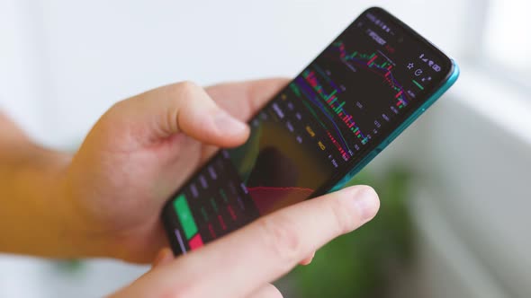 Close Up Businessman Finger Working with Stock Market Data Graph on a Smartphone