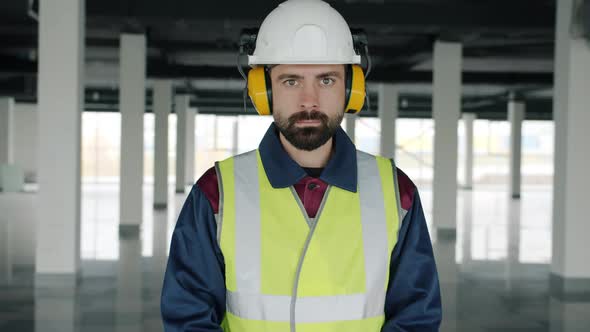 Slow Motion Portrait of Construction Worker Wearing Safety Helmet and Headphones Indoors