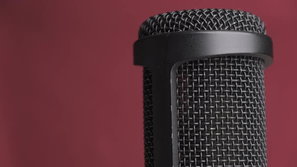 Studio Condenser Microphone Rotates on Red Background with Place for Text