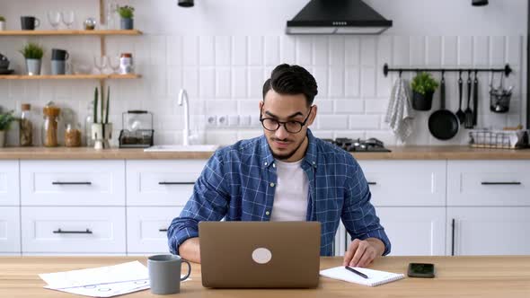 Handsome Positive Indian or Arabian Male Entrepreneur Freelancer Working Remotely While Sitting at