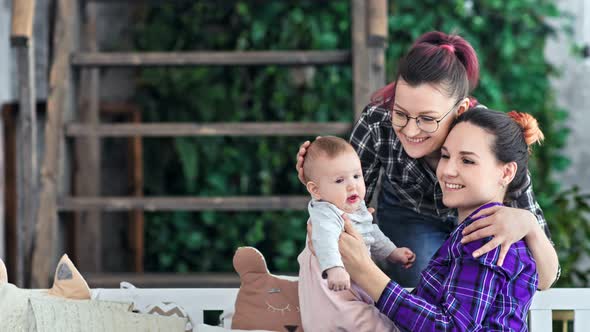 Medium Shot Two Happy Hipster Same Sex Couple Enjoying Motherhood Playing with Cute Baby at Home