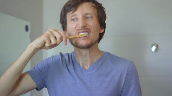 A Young Man Brushes His Teeth with a Brush Made of Bamboo Wood. Zero Waste Concept. Biodegradable