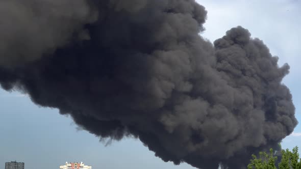 Black Smoke Rises Above the Buildings. A Big Chemical Fire at a Factory Building. Thick Black Smoke